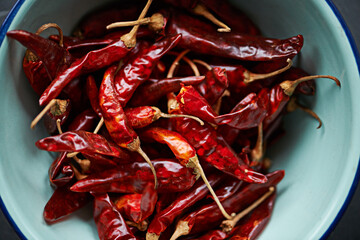 Above, chilli and bowl on closeup for pepper or spice for flavor and dry ingredient for cooking, cuisine and food. Paprika, cayenne or condiment or spicy with red for capsicum or heat in dish or meal - obrazy, fototapety, plakaty