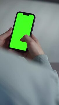 a phone with a green screen in a man’s hands.
Mobile phone with green background close up