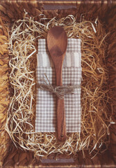 wooden spoon and kitchen towel in a box with straw. Cooking concept. empty wooden spoon on the natural background. Kitchen and cooking accessories. Eco-friendly products. A gift set for the hostess.