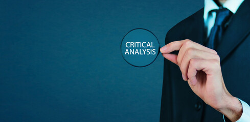 Male hand showing magnifying glass with a Critical Analysis text.