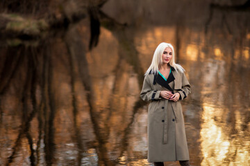 Portrait of a young beautiful blonde girl in the spring near the river.