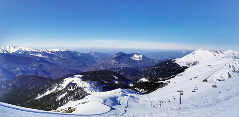 Expansive snowy mountain panorama under a clear blue sky.