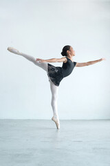 Little girl is practicing ballet in white room at home, ballerina practicing classic choreography,...