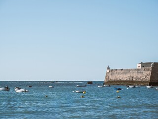 Boats anchored next to the walls of the fort of Santa Catalina in Cadiz