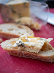 Stilton Blue Cheese with a drizzle of Honey on a French Baguette. Red Cutting Board.