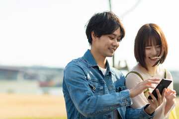 公園でスマホを見るカップル