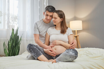 Happy pregnancy time. Caucasian young delighted pregnant woman and her husband spending time...