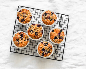 Blackcurrant muffins with crumble on a baking rack on a light background, top view