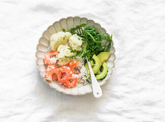 Lunch diet - rice, shrimp, boiled cauliflower, arugula, avocado in one plate on a light background, top view