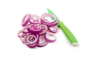 A pile of many slices of a red cooking onions cut into rings with  a green paring knife isolated on...
