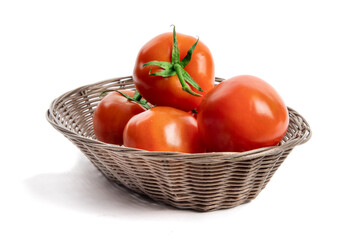 A woven brown basket of fresh ripe red greenhouse tomatoes on the vine isolated on white - Powered by Adobe