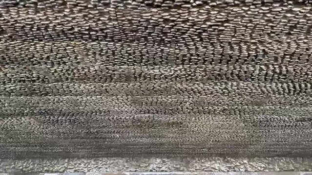 Close up waterfall motion footage on natural andesite stone rough cladding wall texture. Water dropping flowing down on black honed andesite stone, to the pond below.
