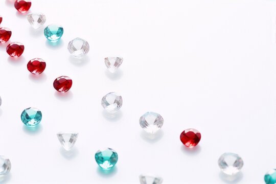 Colorful gemstones scattered on white background, blue green and red gems, still life, art deco.