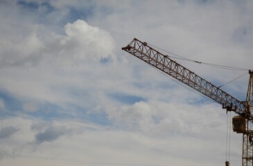 A crane operator comes down after working on a construction crane in the distance. Sky in the clouds