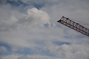 Arrow from a construction crane against a background of blue sky with clouds