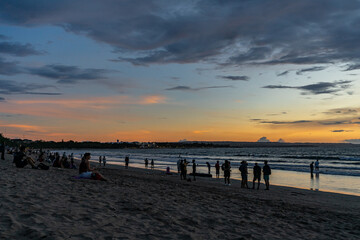 Bali, Indonesia - March 4 2020. silhouettes of tourists enjoying the beautiful sunset at Kuta beach.