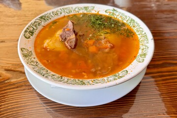 Meat soup in a white plate on a wooden table. Restaurant, menu, recipe. Close-up, front view