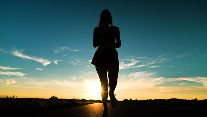 silhouette sports girl running legs along road sunset, joggers park, triathlon competition, sport...