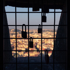 Love lock silhouettes on iron window grill of high medieval tower above city roofs, Florence, Italy