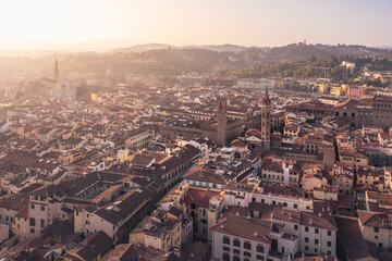 Historical city with high towers on palaces, tiled roofs and distant hills at sunrise, Florence, Italy