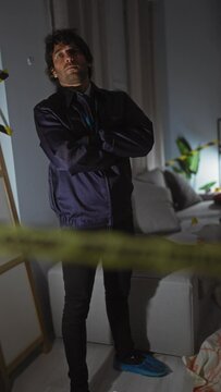 A contemplative young man in a purple forensic suit investigates a crime scene indoors, exuding a detective vibe.
