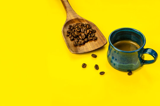 Composition with coffe cup with espresso coffee  and wooden spoon with beans.