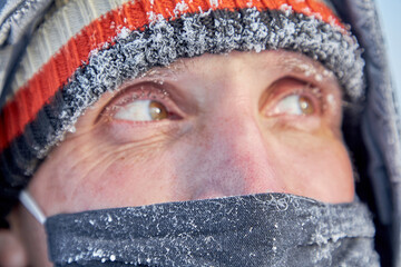 Portrait of a mature man in a knitted hat and a mask on his face in close-up in the cold.A man looks away on a very cold day