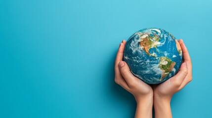 Hands hold the globe up close on a turquoise background, a minimalist concept of planet earth.