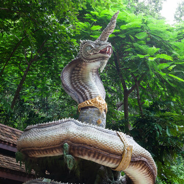 Serpent statue in Monkuware Thao Wessuwan Temple & Garden, surrounded by greenery.