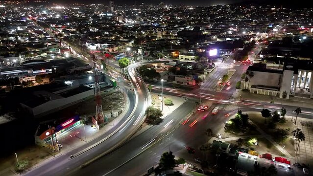 Drone hyperlapse of street intersection with traffic and illuminated buildings at night