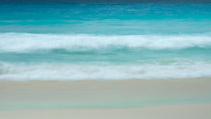 Abstract background of blue sea wave Motion blur sea water and white sand.