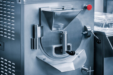 A silver machine with a red button on the side. The machine is used to make food