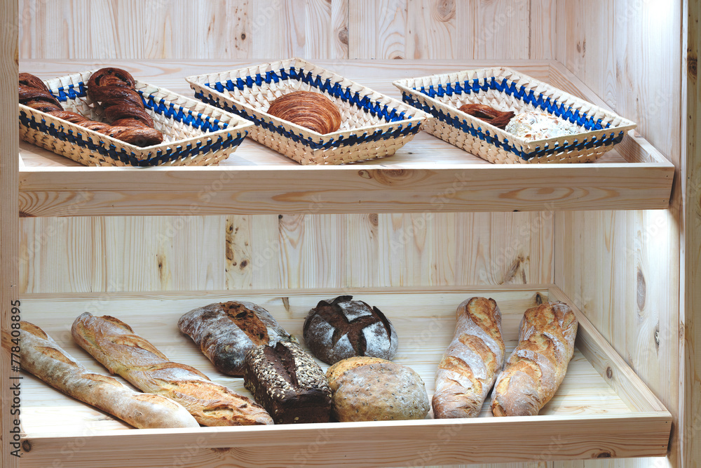 Poster a wooden shelf with a variety of breads on it. the breads are in different shapes and sizes, and som