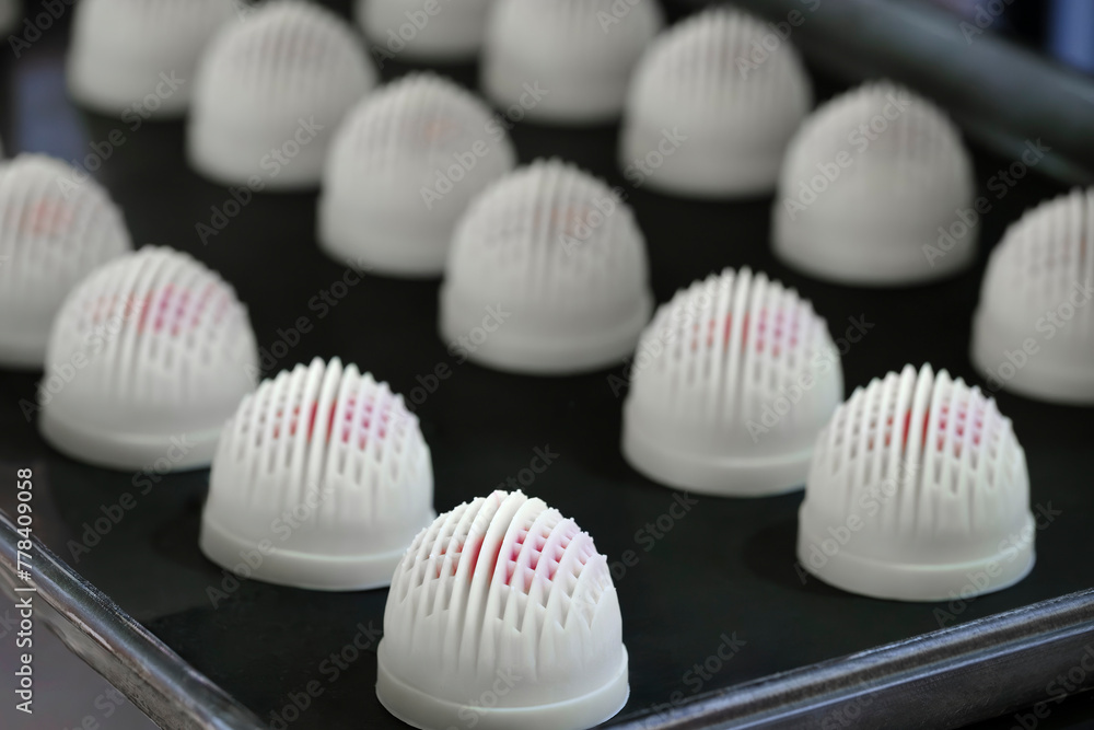 Poster a tray of white and red pastries with a black background. the pastries are arranged in a grid patter