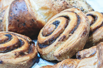 A plate of cinnamon rolls with a few other pastries. The rolls are brown and have a spiral shape