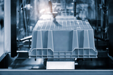 A machine is making a container. The container is blue and white - obrazy, fototapety, plakaty