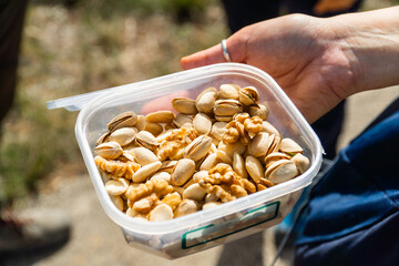 Pistachios and walnuts in a plastic box, tasty and healthy snack to eat outdoors