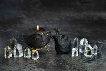 amulet in goat form, crystals and Magic shaman bowl with candle on table, dark background. ...