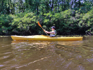 A teenage boy is kayaking on the river in a life jacket and exercising. Active life and rest