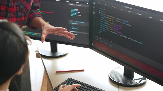 Back end or software developer manager supervising his team on new application program development on debugging and solving complex code algorithms on monitor. Burgeoning