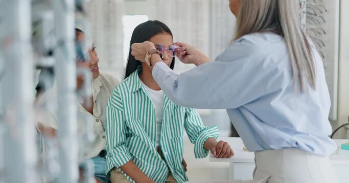 Happy mother, child and glasses with optometrist for sight, vision or eye care at retail shop or store. Mom, daughter and optician helping customers try on spectacles for size, decision or choice