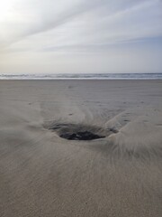 Sand beach with stone after low tide with water streams texture around