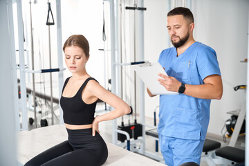 Doctor questioning female patient in kinesiology clinic