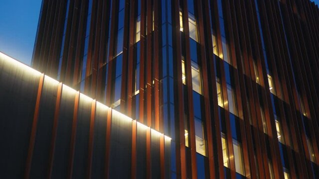 A modern scyscraper building with a lot of windows is lit up at night