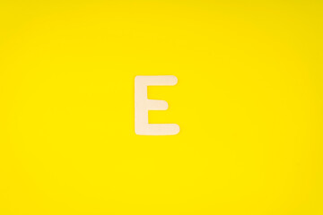 Letter E in wood on yellow background