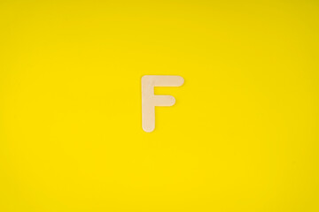 Letter F in wood on yellow background