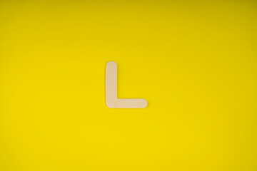 Letter L in wood on yellow background