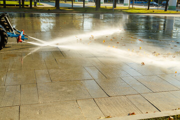 Watering streets and sidewalks with special equipment using jets of water to wash away dust and...