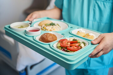 Male nurse is serving dietary meal in medical facility ward