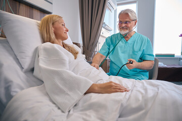 Doctor conducting physical examination of female patient during ward round